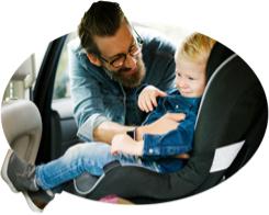 Dad buckles his son into a child safety seat.
